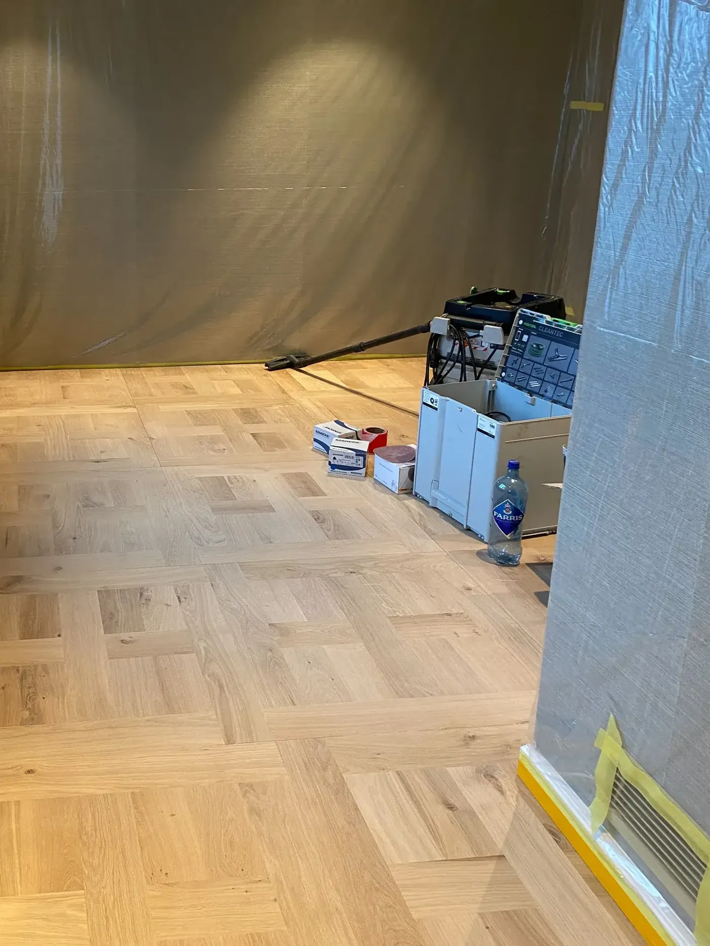 Mønsterparkett slipt ned til rent tre, rommet dekket til med plast under arbeidet